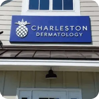 Blue sign with white 3D text and pinapple logo over tan vinyl business store. Text reads: Charleston Dermatology